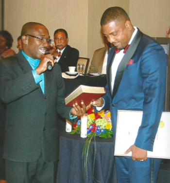 Rev. Hugh Hamilton (right) presents bible to West Indies Cricket Board’s president David Cameron.