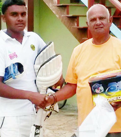 Sam Sooppersaud (right) presents cricket gears to young Alex Algoo during his visit to Guyana in July. Photo courtesy of Kaieteur News.