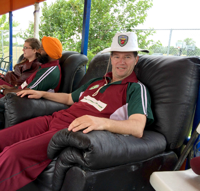 NVCC vice captain Bernie Peacock takes a well-deserved rest after his haul of 3 wickets for 25 runs in 5.5 overs. Also pictured is NVCC member Chandanpreet Virk and his wife Michelle. Top photo, team picture with Bradshaw CC left (yellow and green) and NVCC on right (maroon and green).